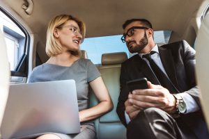 businessman and assistant working in car with laptop and smartphone