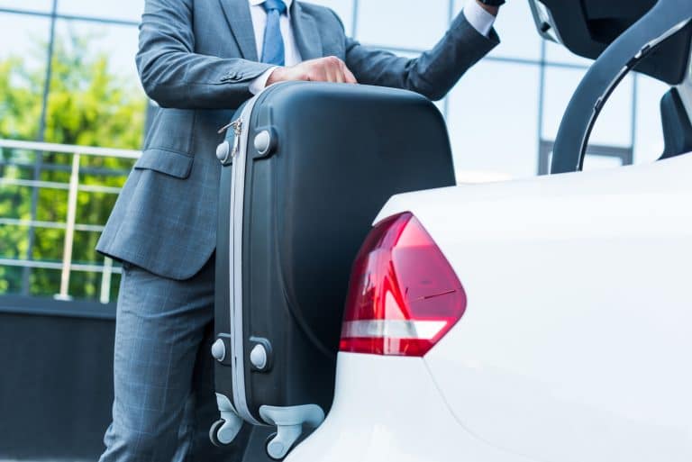 Chauffeur placing luggage in boot of limousine