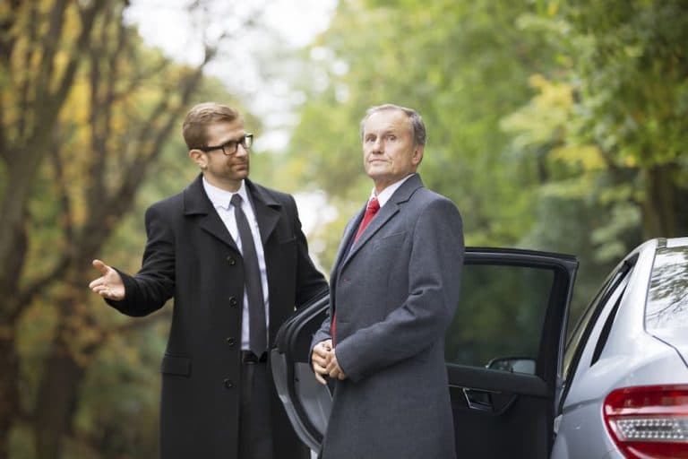 chaffeur opening car door for businessman