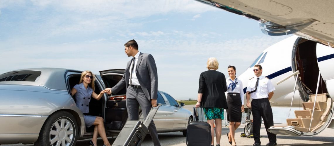 woman getting out a limo on the tarmac with a man helping her and flight crew standing outside the plane