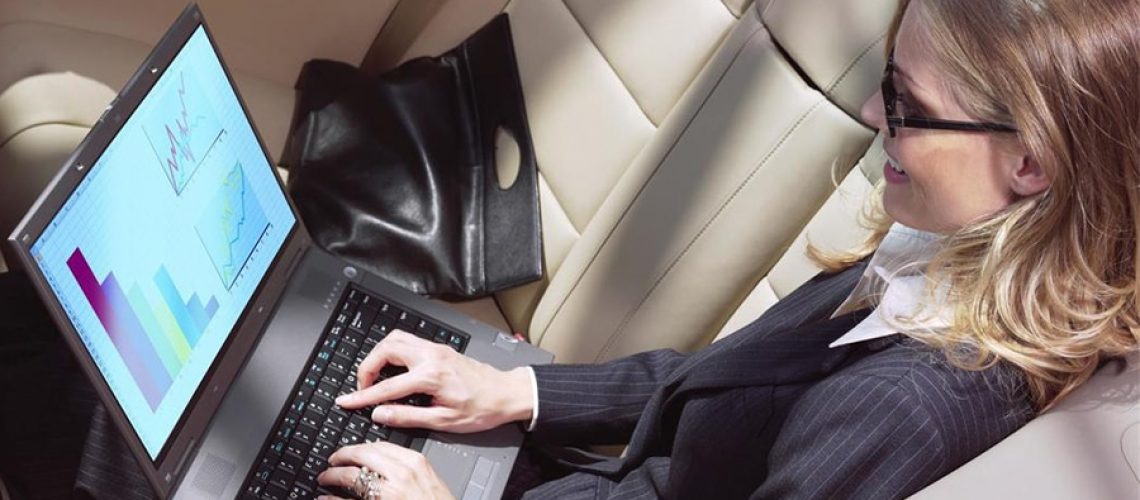 Businesswoman working on laptop in limousine